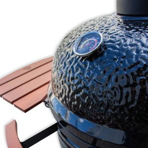 Detailansicht des BBQ First Grill: Schwarzer Keramikgrill mit Thermometer und Holzablage.