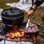 Petromax Dutch Oven Set FT9-T-Scrub: Gusseisen-Topf und Pfanne über offenem Feuer mit Fleisch.