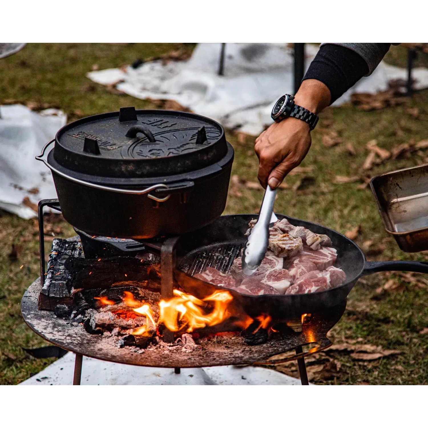 Petromax Dutch Oven Set FT9-T-Scrub: Gusseisen-Topf und Pfanne über offenem Feuer mit Fleisch.