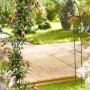 Dunkelgrüne Metall Rankhilfe mit blühenden rosa Rosen im Garten über einem Holzweg.