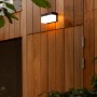 Schwarze, eckige Lutec LED Solar-Wandleuchte Fran an einer Holzwand. Mit Bewegungsmelder.