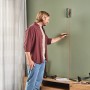 Mann benutzt Bosch UniversalWallLevel Laser-Wasserwaage zur vertikalen Ausrichtung an einer Wand.