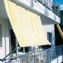 Floracord Balkonverkleidung Bausatz II, gelb-weiß gestreift, als Sonnenschutz am Balkon montiert.