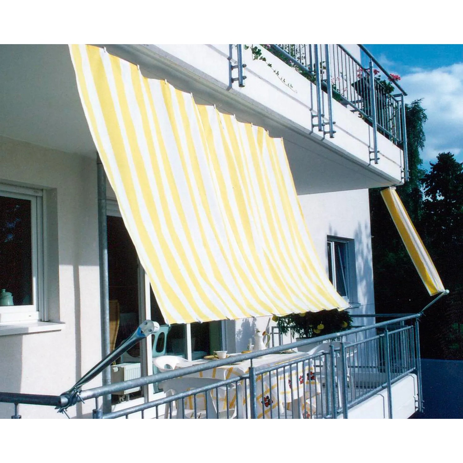 Floracord Balkonverkleidung Bausatz II, gelb-weiß gestreift, als Sonnenschutz am Balkon montiert.