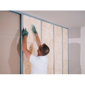 Ein Mann montiert eine Isover Trennwandplatte Akustic TP 1 Lanaé (60mm) in ein Metallgerüst.