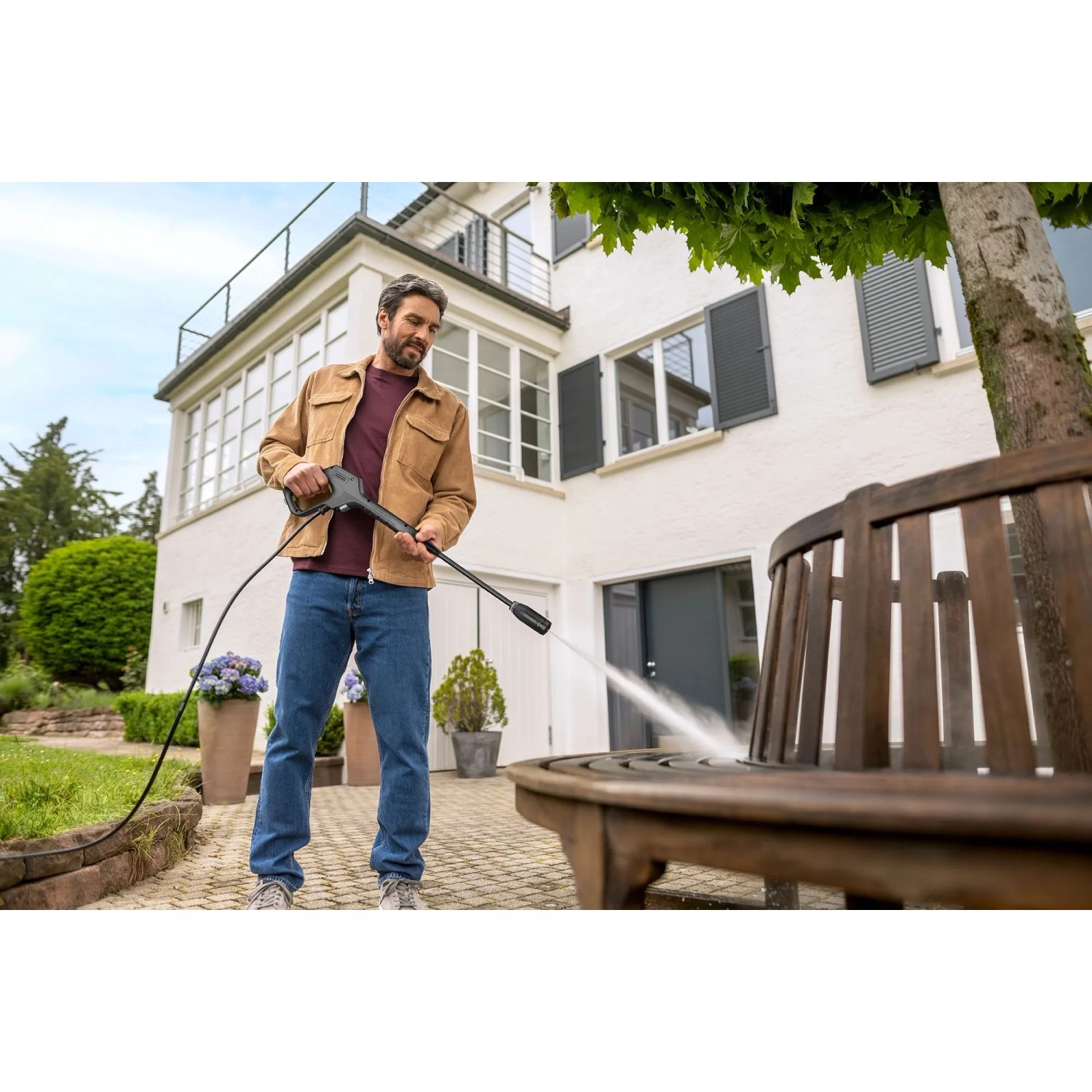 Mann reinigt Holzbank mit Kärcher Hochdruckreiniger K 3 Premium Car & Home. Inkl. Zubehör für Auto & Garten.