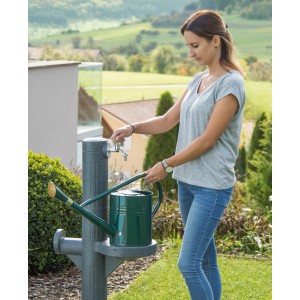 Frau befüllt Gießkanne an Arves Wasser-Zapfstelle Premium Black Granit im Garten.