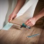 Wolfcraft Einpass-Set für Laminat: Mann nutzt Einpasser an Laminatboden, Bleistift liegt bereit.