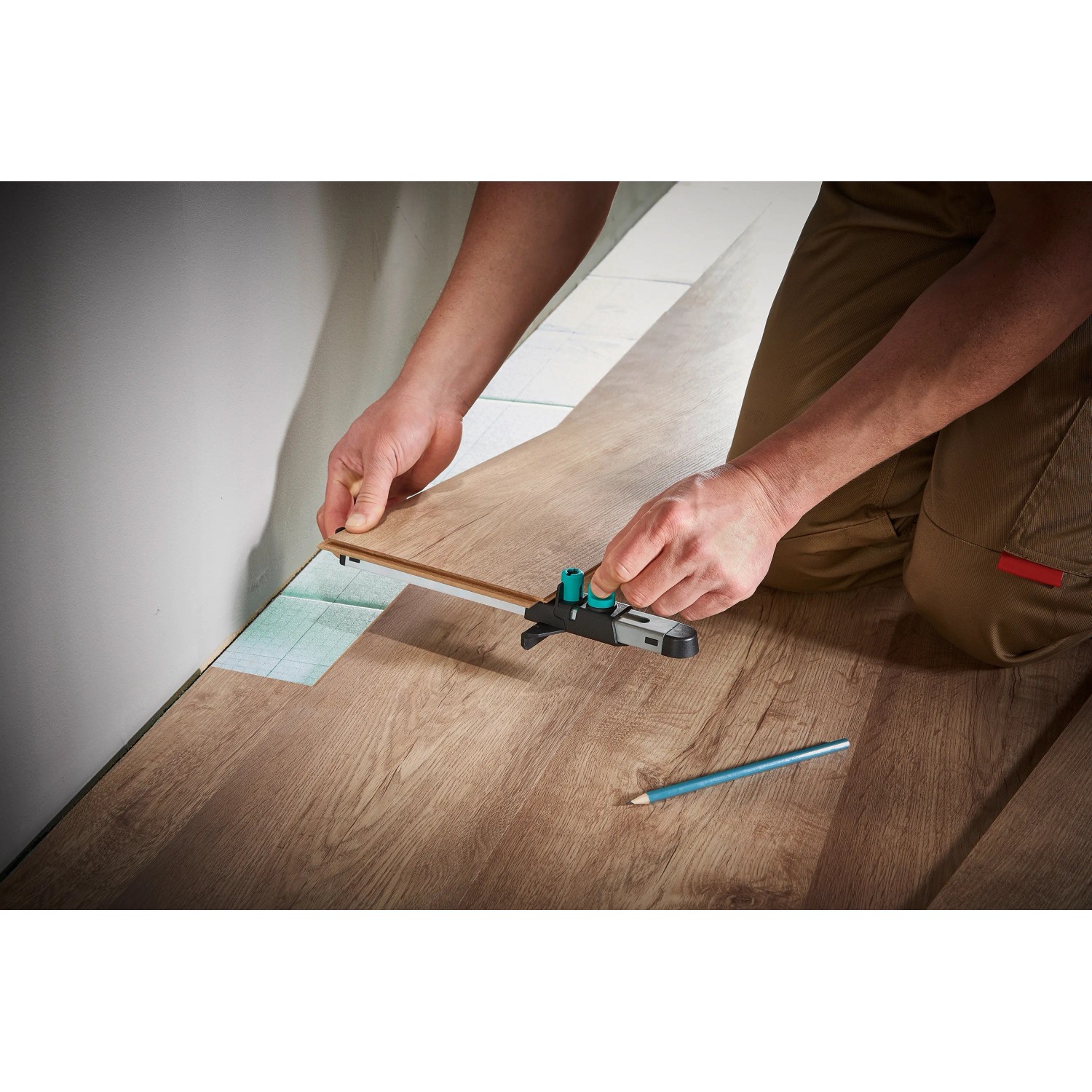 Wolfcraft Einpass-Set für Laminat: Mann nutzt Einpasser an Laminatboden, Bleistift liegt bereit.