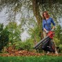 Frau nutzt Einhell Akku-Laubsauger Venturro 18/210 zum Aufsaugen von Laub im Garten.
