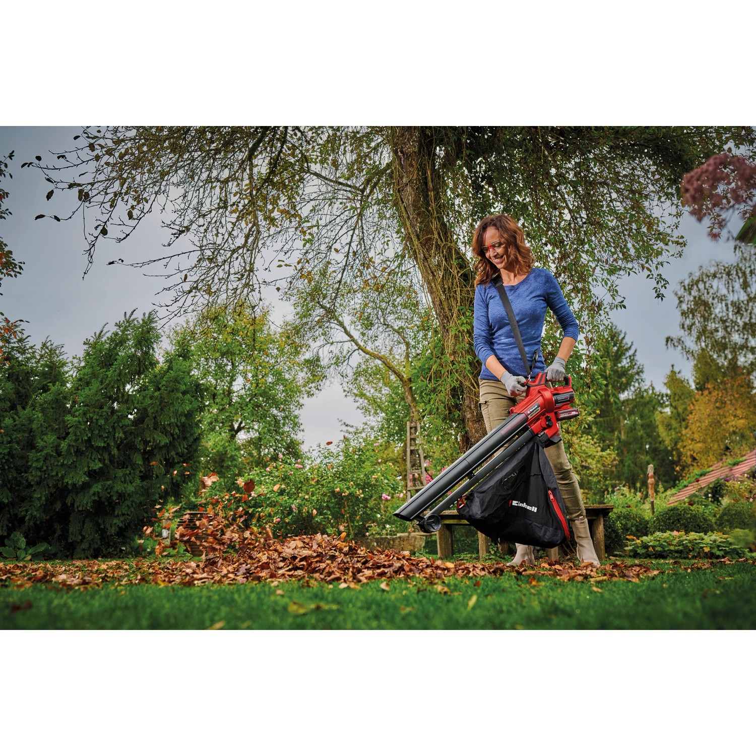 Frau nutzt Einhell Akku-Laubsauger Venturro 18/210 zum Aufsaugen von Laub im Garten.