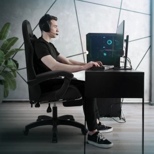 ML-Design Gaming Stuhl mit Fußstütze, schwarz, Kunstleder, verstellbar. Gamer sitzt am Schreibtisch.