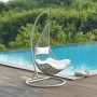 Vente-unique Hängesessel Orosi hellgrau aus Polyrattan mit weißem Kissen am Pool auf Holzdeck.