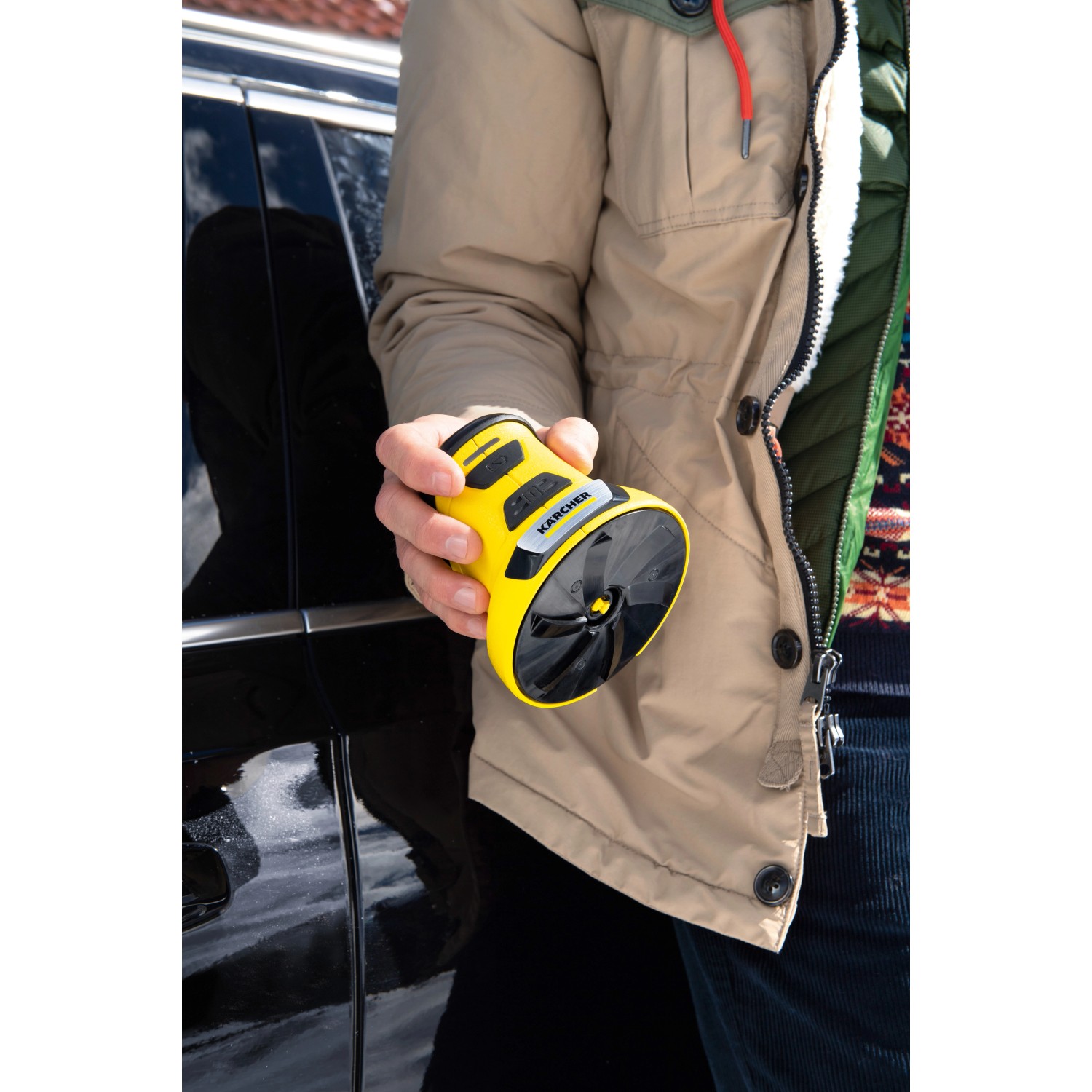 Gelber Kärcher EDI 4 Akku-Eiskratzer in Hand vor Auto. Praktischer Helfer für den Winter.