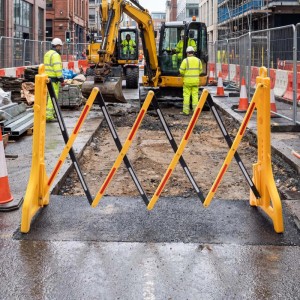 Gelbes ausziehbares Absperrgitter aus Kunststoff mit reflektierenden Streifen sichert eine Baustelle. Flexibles Scherengitter für Verkehr.