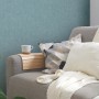 Blaue, leicht strukturierte Vliestapete Uni Matt von OBI an der Wand hinter einem Sofa.