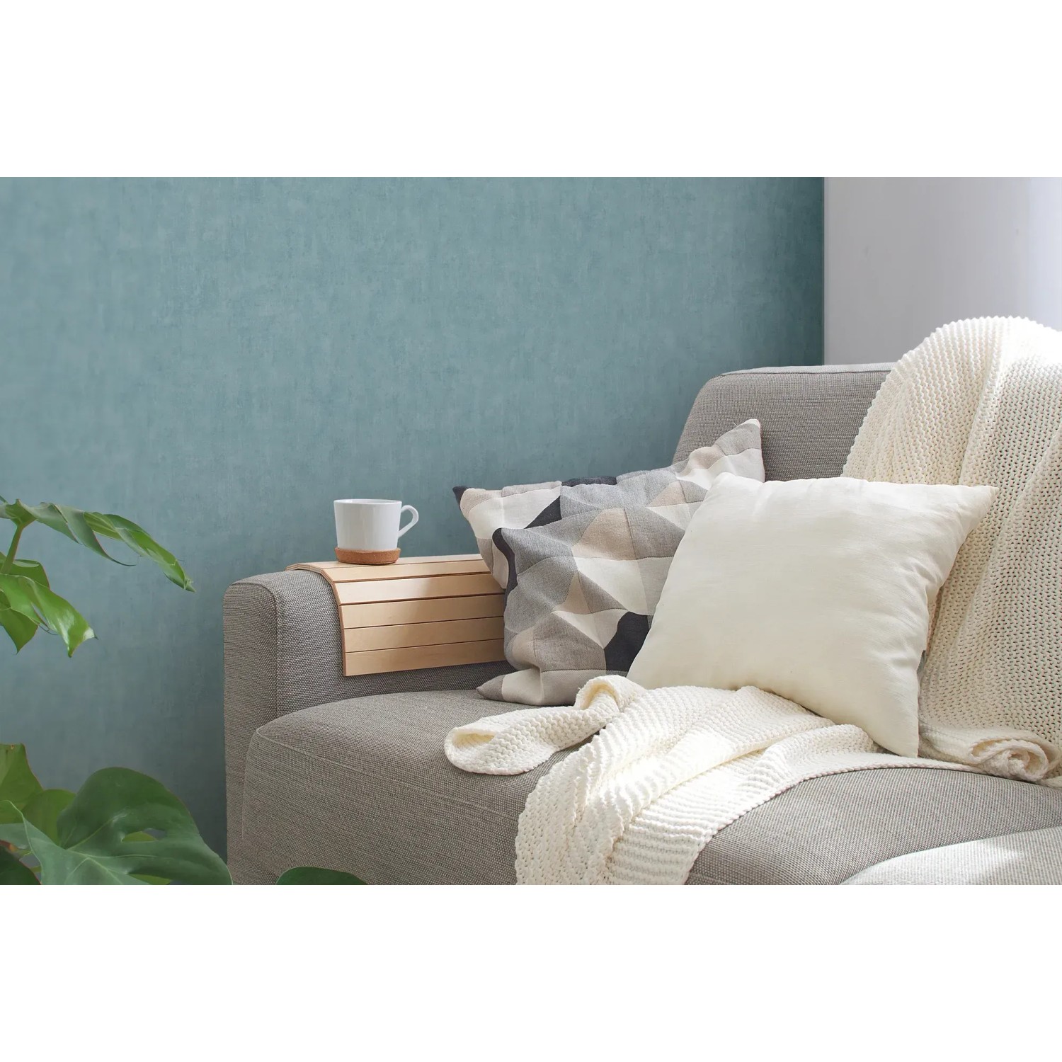 Blaue, leicht strukturierte Vliestapete Uni Matt von OBI an der Wand hinter einem Sofa.