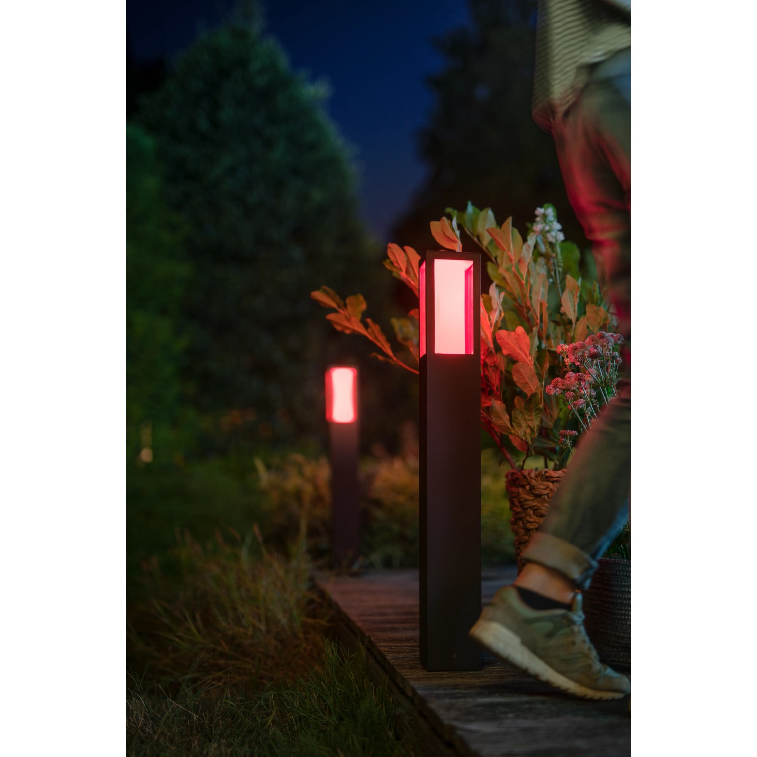 Philips Hue Impress LED-Wegeleuchte, schwarz, mit rotem Licht im Garten.