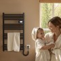 Schwarzer Emke Handtuchwärmer elektrisch mit LED-Display, Handtücher hängen, Mutter mit Kind im Bademantel.
