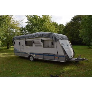 Graues GreenYard® Wohnwagen Schutzdach (650 cm) auf einem Wohnwagen mit Spanngurten befestigt.
