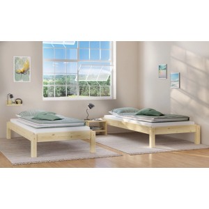 Zwei unbehandelte Kiefer Einzelbetten (90x200) mit Matratze und Kissen in hellem Raum. Erst-Holz Futonbett.
