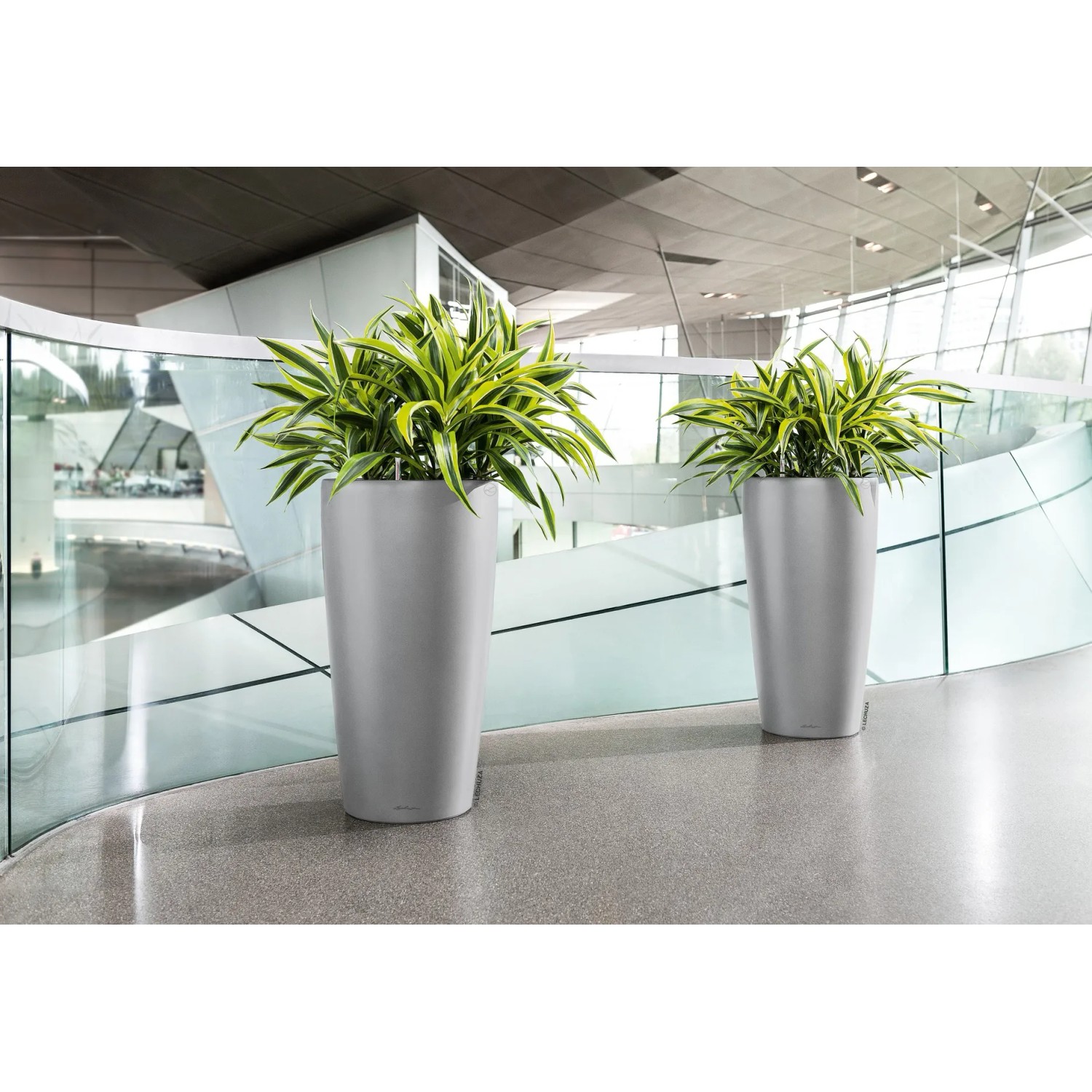 Lechuza Rondo Premium Pflanzsäule, Ø 33 cm, silber metallic, mit grünen Pflanzen.