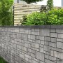 Grau-anthrazitfarbene EHL Mauer aus Tribus Quada Mauersteinen im Garten.