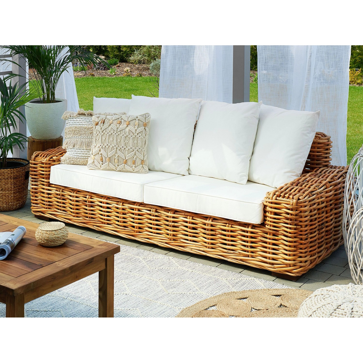 Beiges Beliani Gartensofa aus Rattan mit weißen Kissen (94x218x67 cm).
