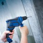 Blaue LUX Schlagbohrmaschine E-BMS-21 mit Tiefenanschlag beim Bohren in Beton.