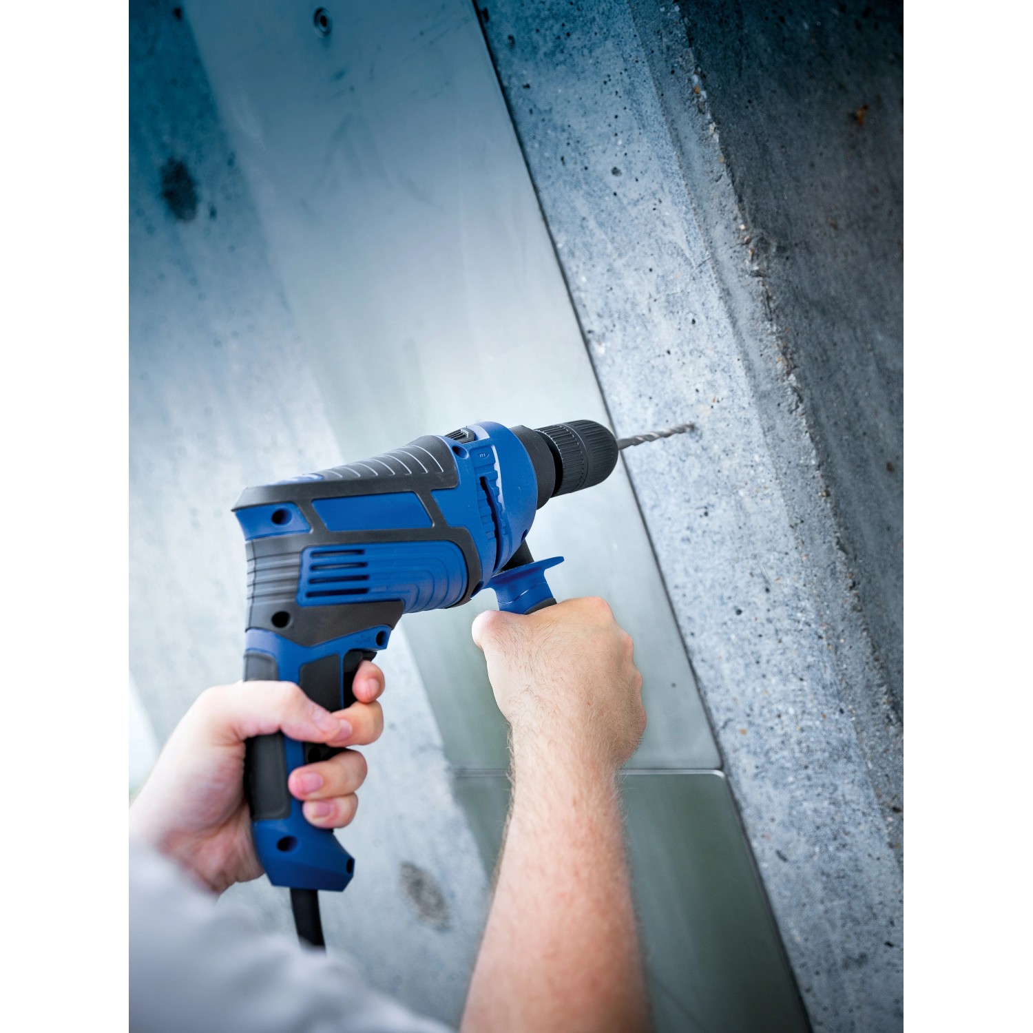 Blaue LUX Schlagbohrmaschine E-BMS-21 mit Tiefenanschlag beim Bohren in Beton.