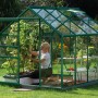 Grünes Vitavia Gewächshaus Venus 5000 mit Frau bei der Pflanzenpflege im Garten.
