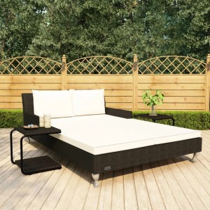 Doppelte Sonnenliege aus Rattan (schwarz) mit cremeweißen Kissen und Beistelltischen.