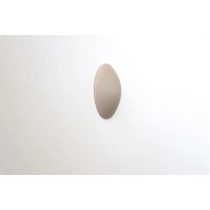 Beiger, ovaler selbstklebender Wand-Türstopper aus Kunststoff an weißer Wand. Schützt Wände vor Beschädigungen. Türzubehör.