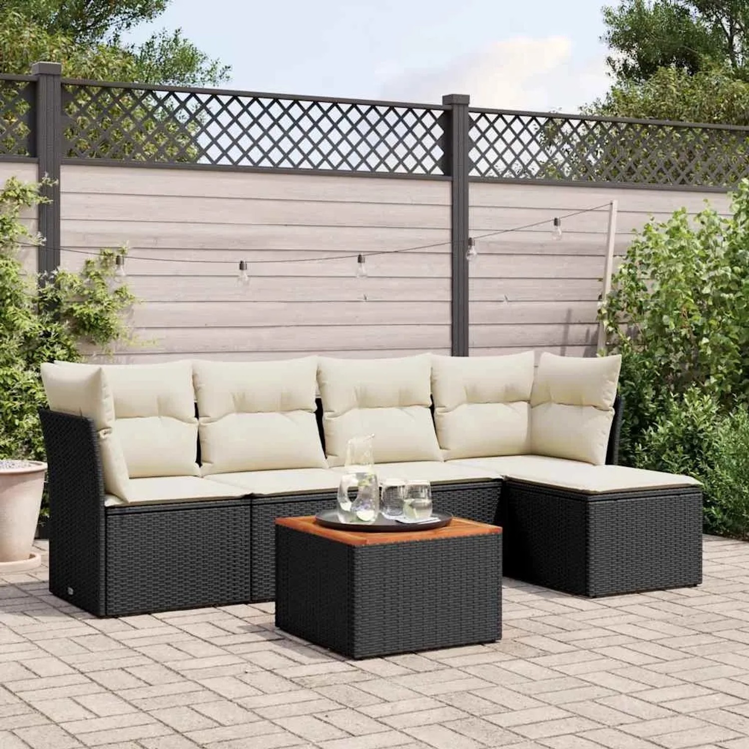 Schwarze 6-tlg. Garten-Sofagarnitur aus Poly Rattan mit cremefarbenen Kissen und Tisch.