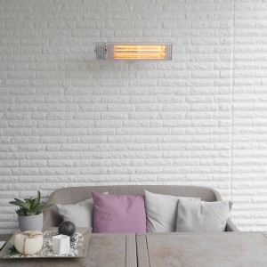 Silberner Vasner Infrarot-Heizstrahler Appino 20 an weißer Wand über Sitzgruppe.