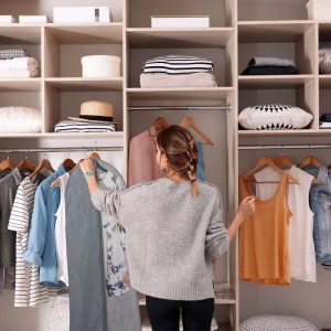 Frau hängt grauen Relaxdays Kleidersack (3er Set) in Schrank. Schutzhülle mit Reißverschluss, transparent.