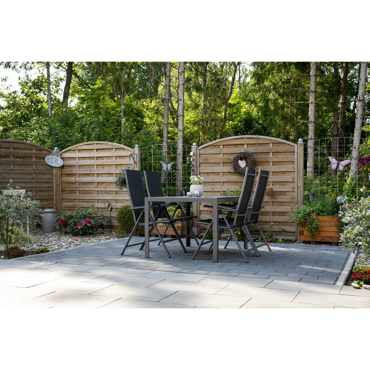 Verlegtes Diephaus Pflaster Mika Anthrazit 30x20x6 cm im Garten mit Sitzgruppe vor Holzzaun.
