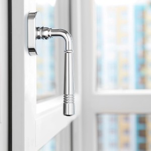 Glänzender SOTECH Fenstergriff FREJA Chrom poliert am weißen Fenster. Eleganter Beschlag.