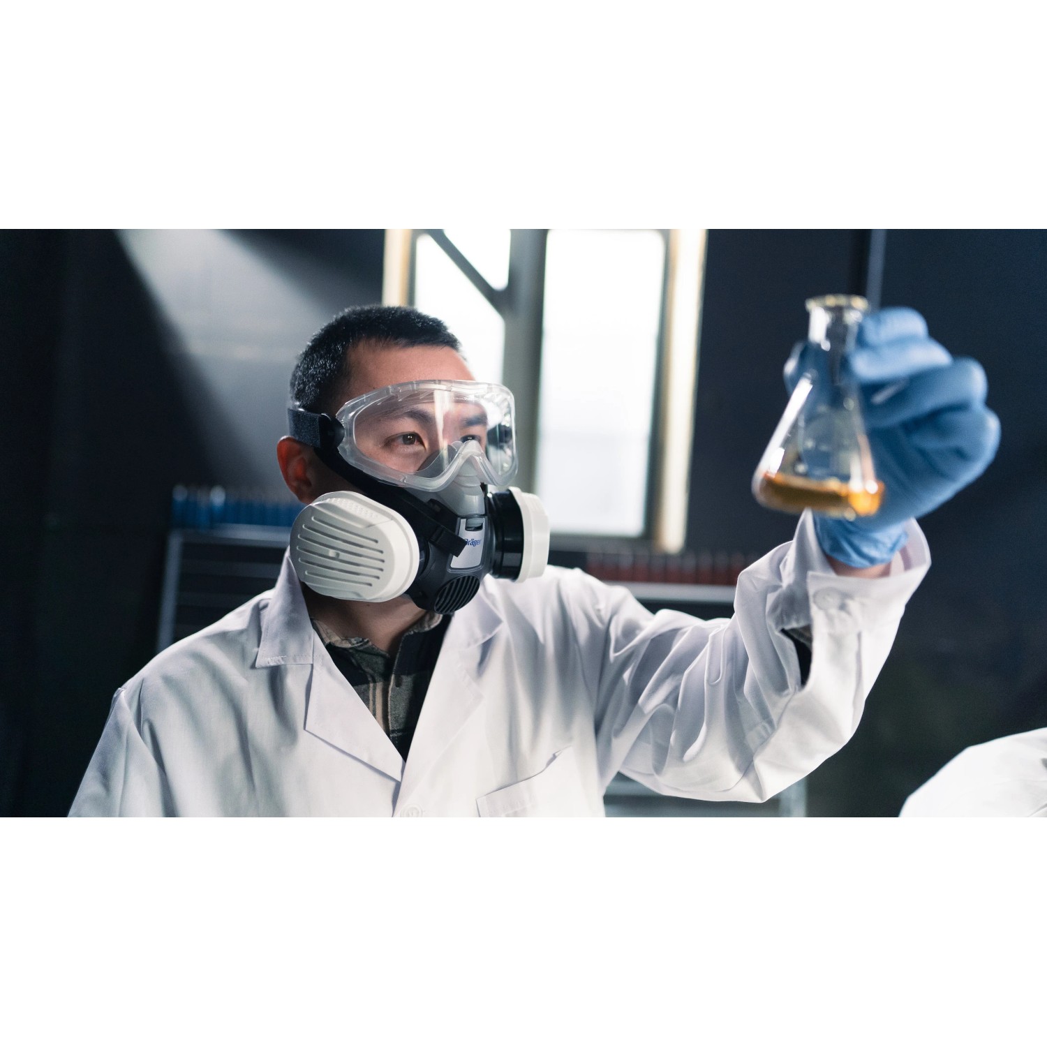 Mann mit Dräger Halbmaske X-plore 3300 Chemiearbeiterset und Schutzbrille im Labor.