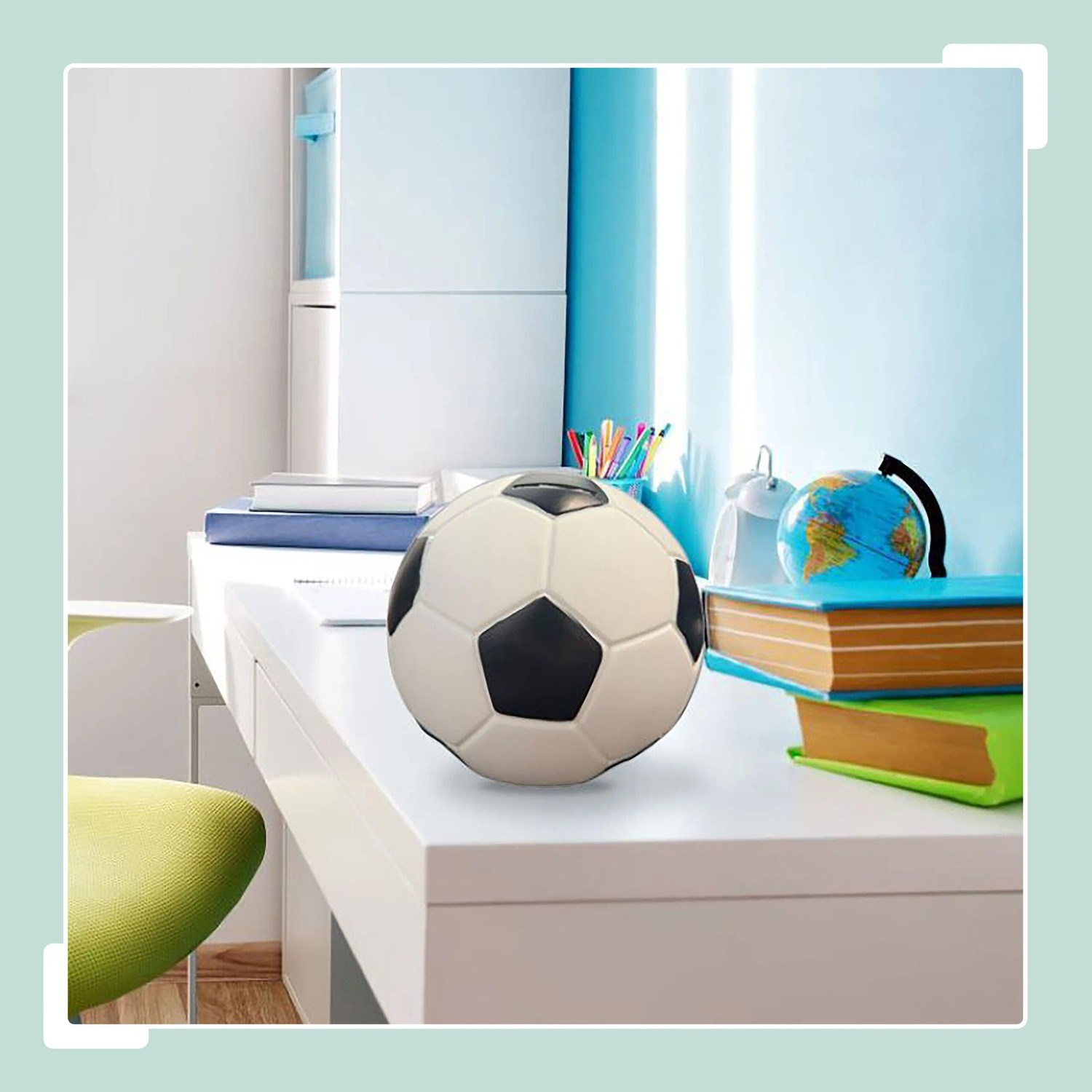 Schwarze-weiße Fußball Spardose aus Kunstharz auf Schreibtisch, 15x15cm.