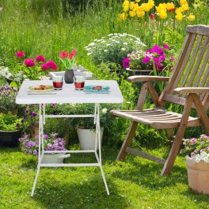 Weißer quadratischer Klapp-Gartentisch aus Kunststoff und Stahl, gedeckt im grünen Garten. Ideal für Outdoor-Mahlzeiten.
