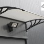 Transparentes DELUKE Vordach ESAO aus Kunststoff mit schwarzer Halterung über einer Tür.