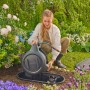 Frau installiert Gardena Undercover Schlauchbox RollUp M im Garten.