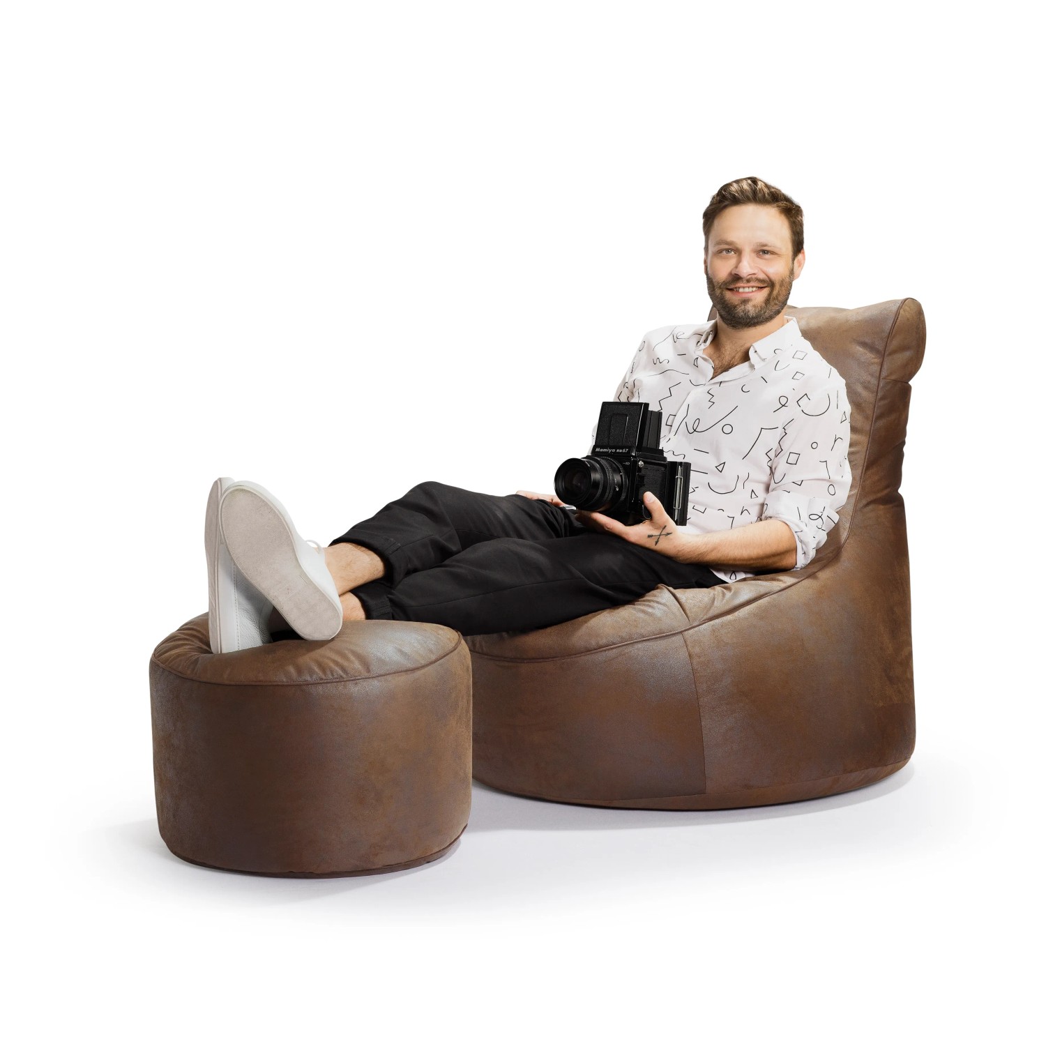 Sitting Point Hocker DotCom mittelbraun mit Person und Kamera auf Sitzsack und Hocker.