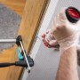 Person montiert Türfutter mit wolfcraft Montageset. Bauschaum wird zwischen Zarge und Wand gespritzt, Spannwerkzeug fixiert.