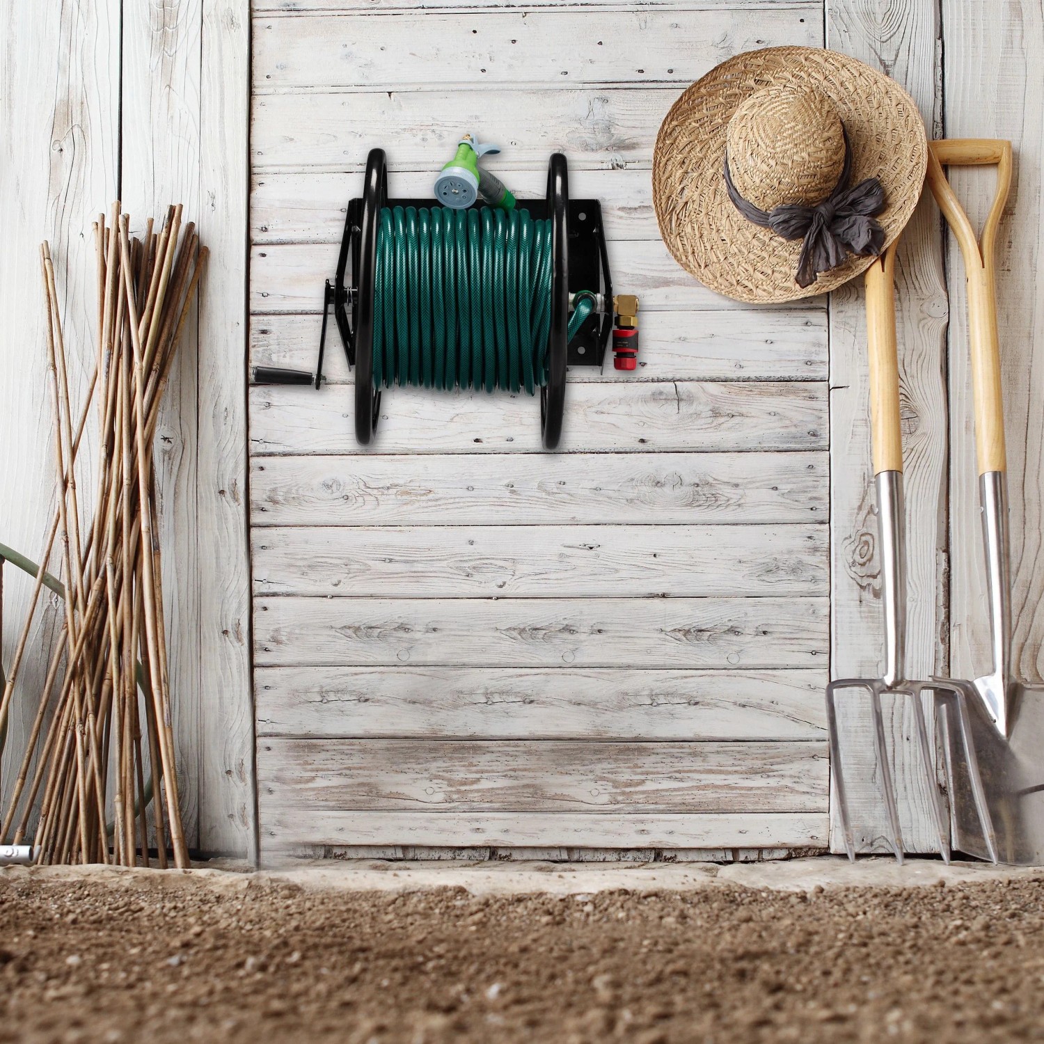 Schwarzer Relaxdays Wand-Schlauchaufroller aus Stahl mit grünem Gartenschlauch an heller Holzwand, umgeben von Gartenwerkzeugen.