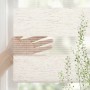 Beiges Doppelrollo mit transparenten und blickdichten Streifen, von Hand verstellt für regulierbaren Sichtschutz am Fenster.