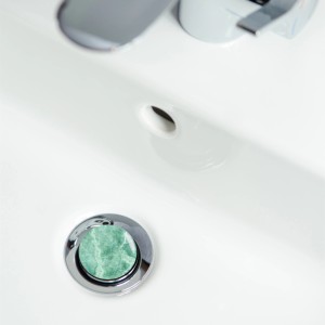 Sanilo Waschbeckenstöpsel in Marmor Grün im weißen Waschbecken.