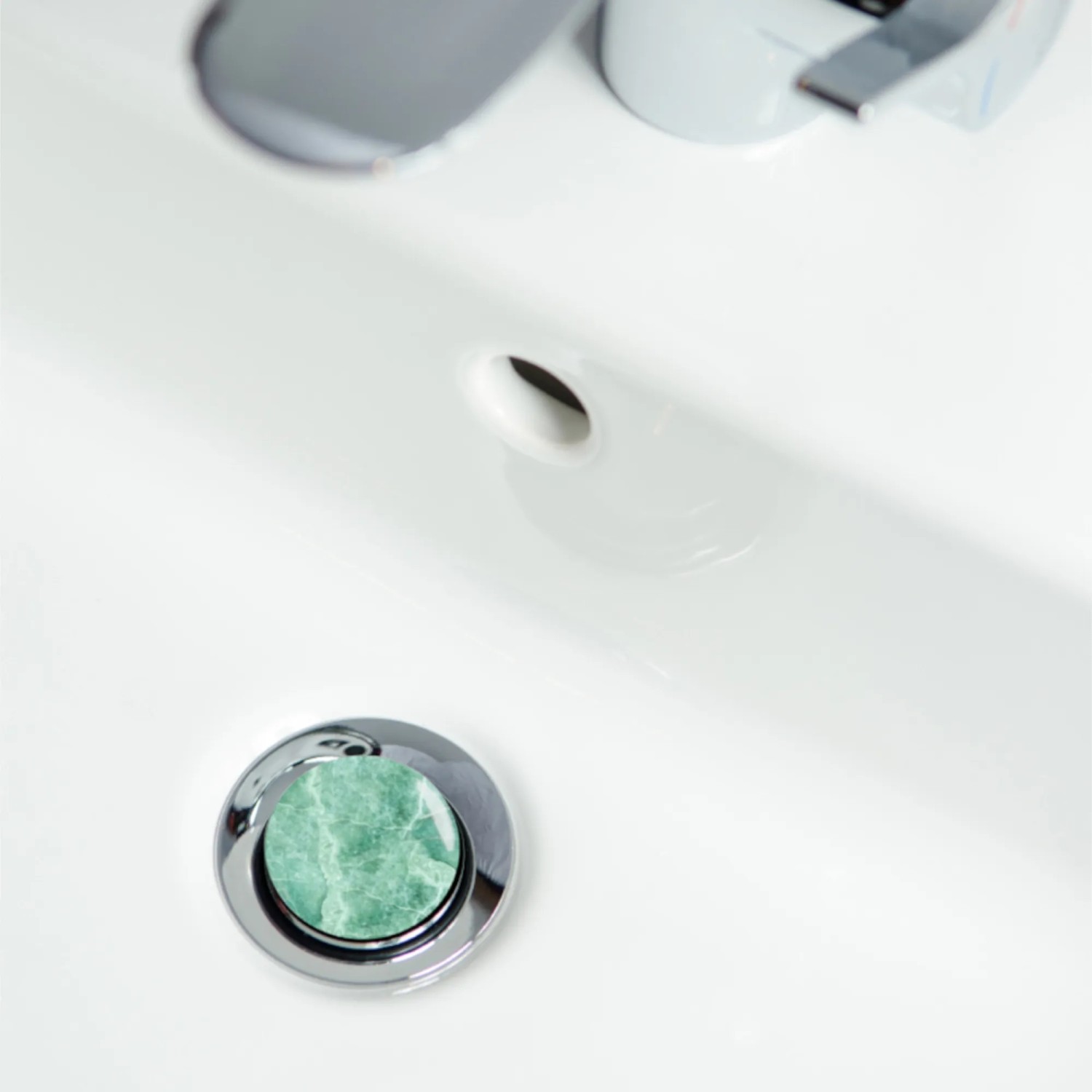 Sanilo Waschbeckenstöpsel in Marmor Grün im weißen Waschbecken.