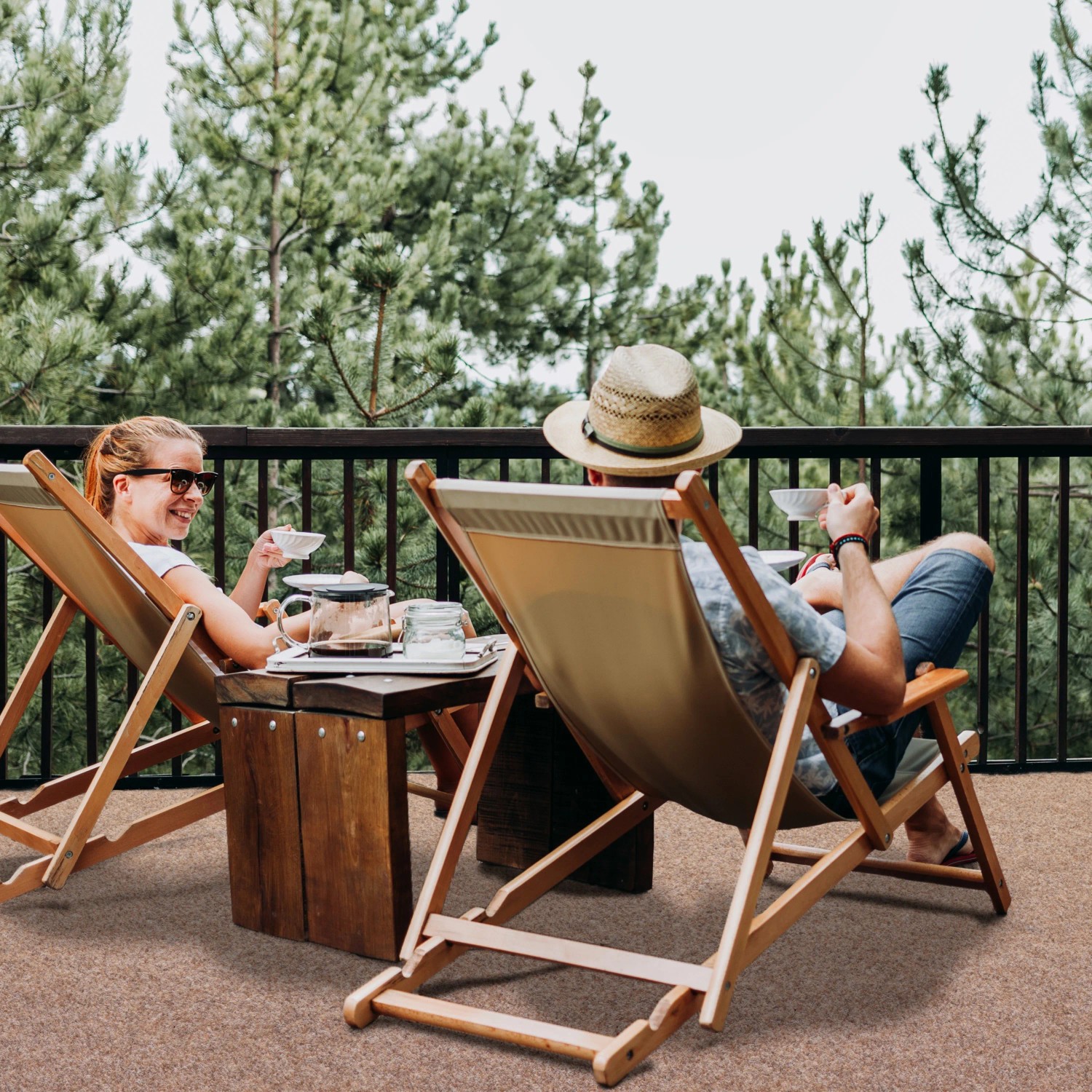 Personen entspannen auf Primaflor Rasenteppich Green Beige auf einer Terrasse.